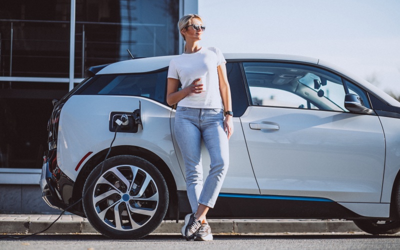 Sieviete veic elektroauto uzlādi. Sieviete veic elektroauto uzlādi.